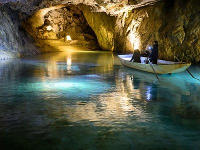 An underground lake with a little boat on it with people.