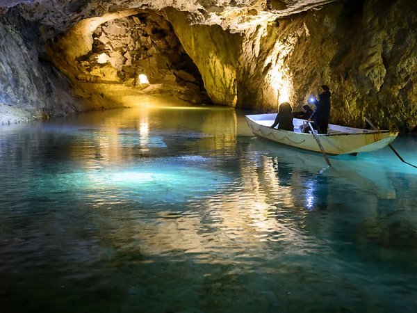 An underground lake with a little boat on it with people.