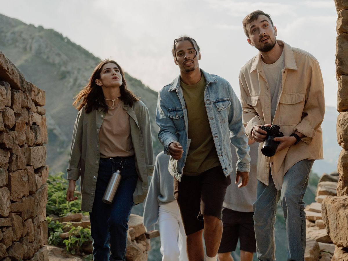 A group of travellers on a mountain path, looking up at the view