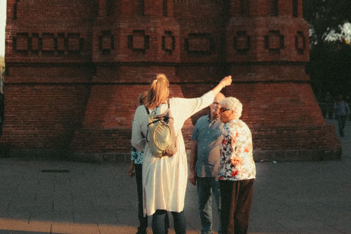 A guide pointing out a brick tower to a small group in the late sun